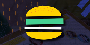 Imagem gráfica que mostra um sanduíche, que parece um hambúrguer, feito de formas geométricas amarelas, verdes e brancas, que ocupa o centro da cena. Ao fundo, bastante escura e desfocada, aparece uma  imagem de uma tela de computador e alguns símbolos laranjas ovalados do lado esquerdo. 